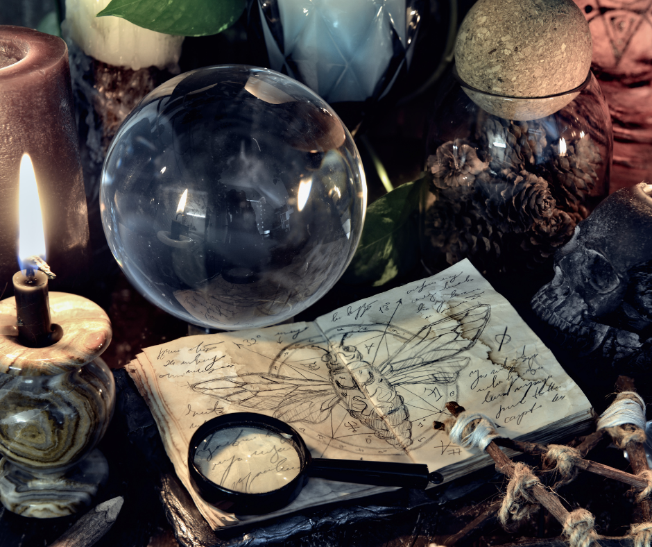 The tools of the Craft. Tools of Wicca, Tools of witchcraft. Photo of a layout of a book with a moth drawn in it, a crystal ball, and lit candle.